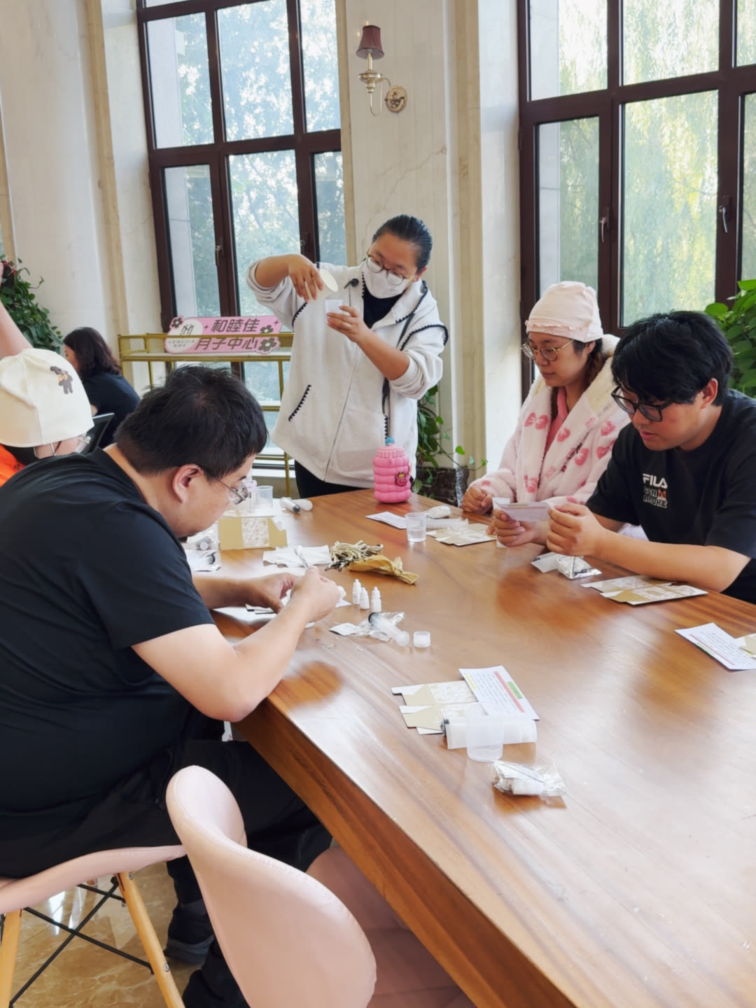 老师在桌边带着妈妈们做护手油